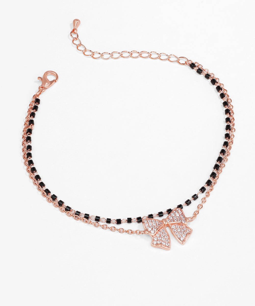 Bracelet with black beads and a rose gold bow charm on a white background