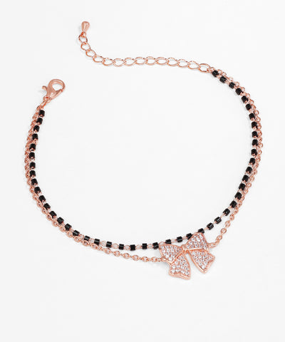 Bracelet with black beads and a rose gold bow charm on a white background