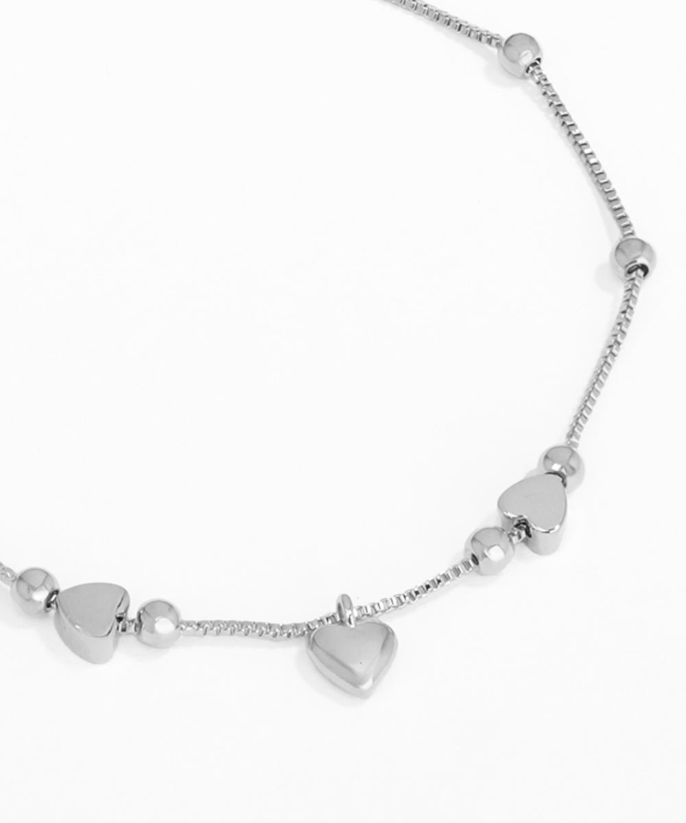 Silver necklace with heart-shaped pendants on a white background