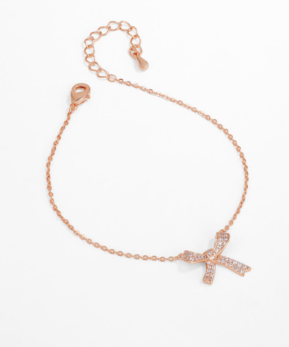 Rose gold bracelet with a cross charm on a white background