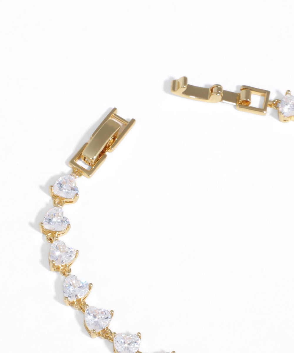 Gold bracelet with clear gemstones on a white background