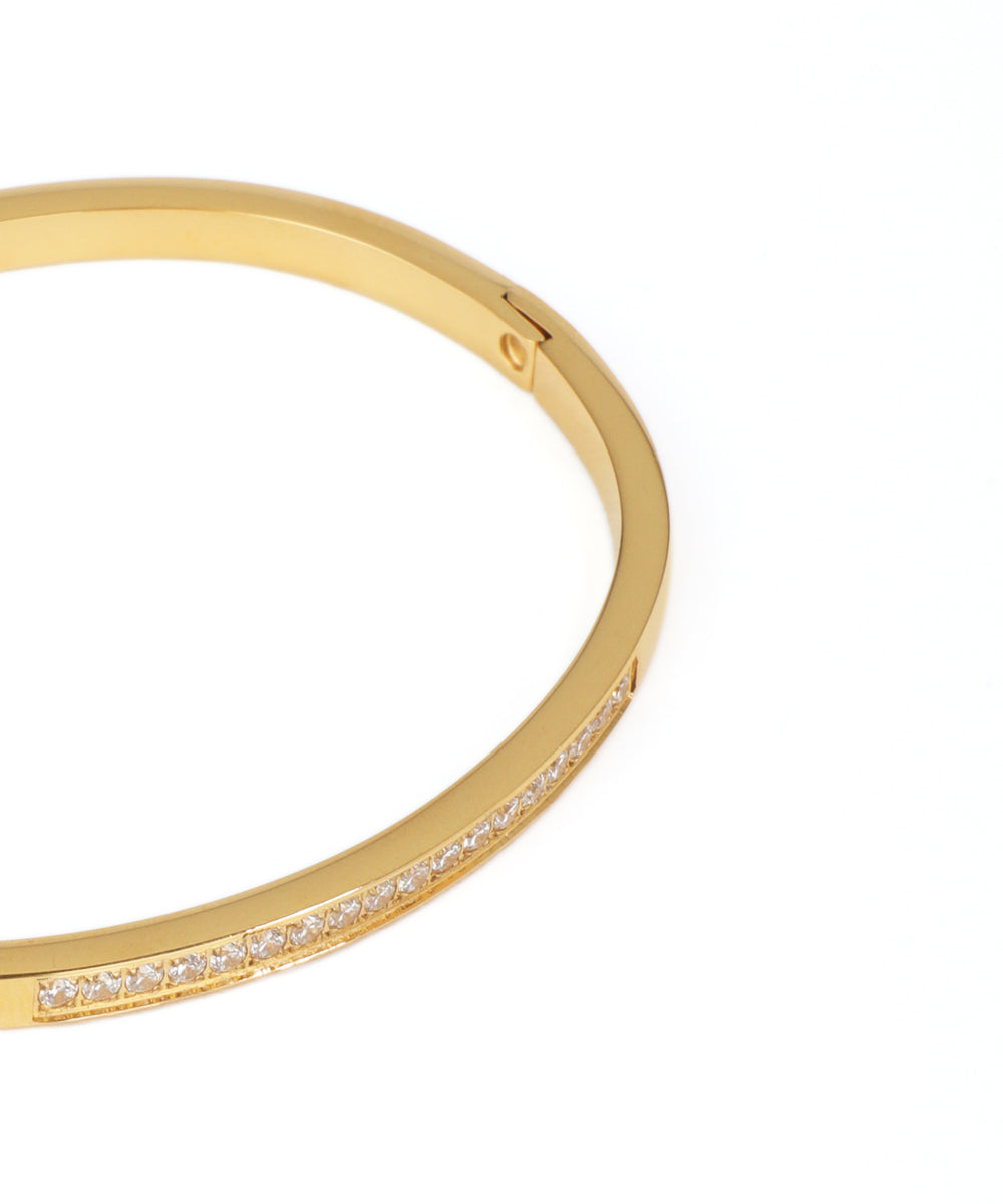 Gold bangle with embedded diamonds on a white background