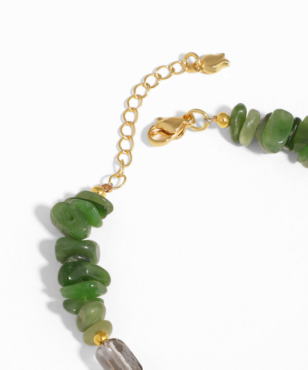 Green beaded bracelet with gold chain on a white background