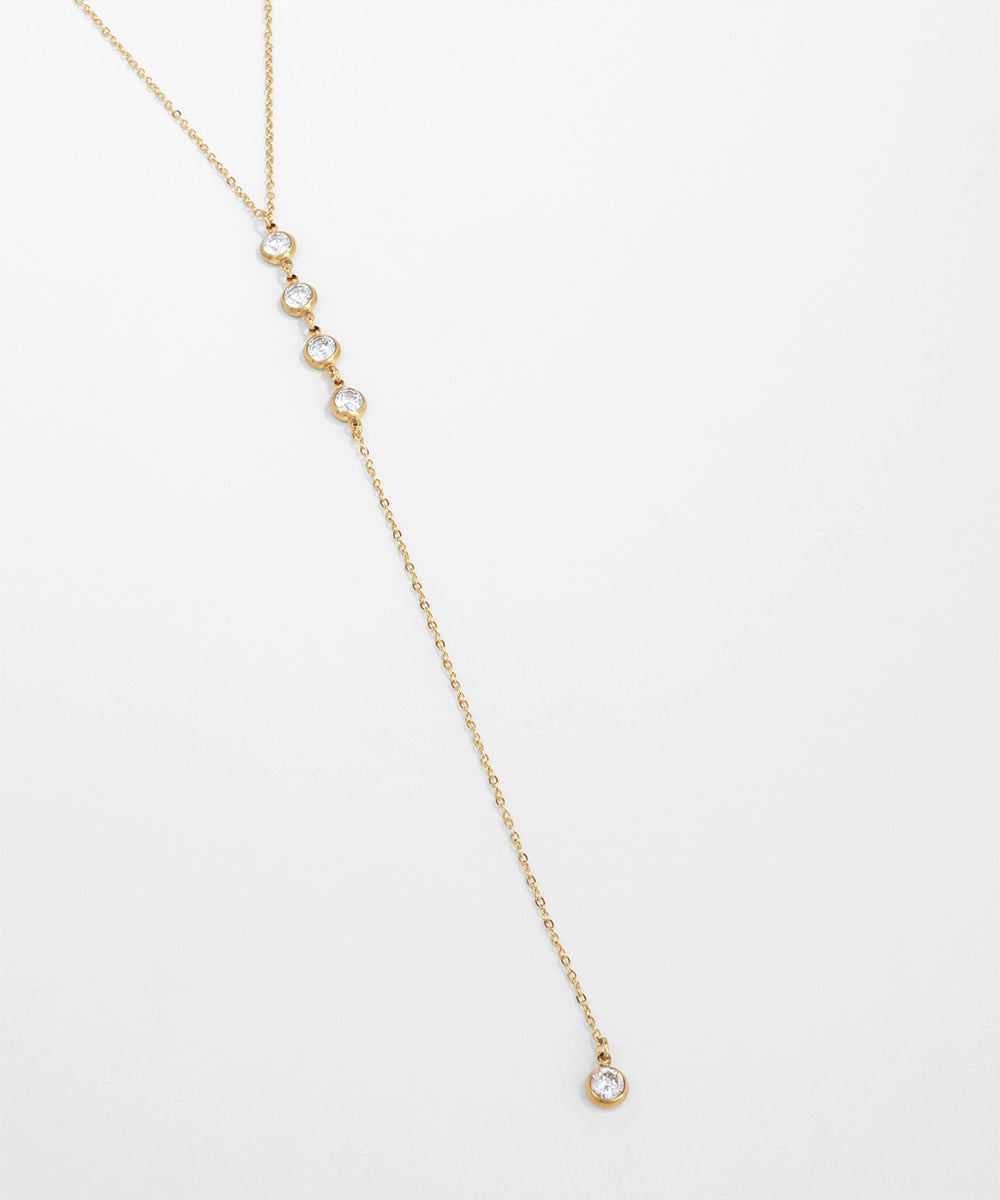 Delicate gold necklace with small diamonds on a light gray background