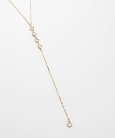 Delicate gold necklace with small diamonds on a light gray background