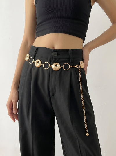 Person wearing black pants with a gold chain belt on a white background