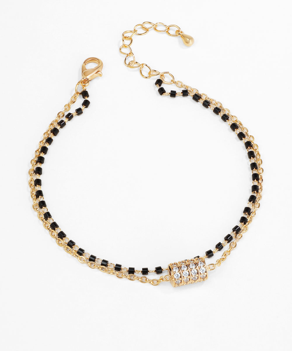 Gold bracelet with black beads and a clasp on a white background