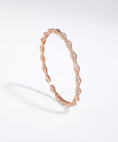 Rose gold bracelet with diamond accents on a light gray background