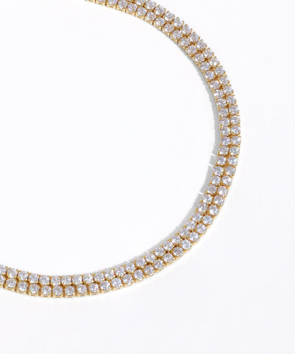 Gold necklace with clear gemstones on a white background