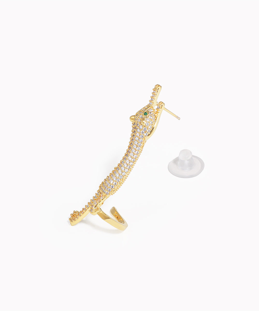 Gold earring with green gemstone on a white background