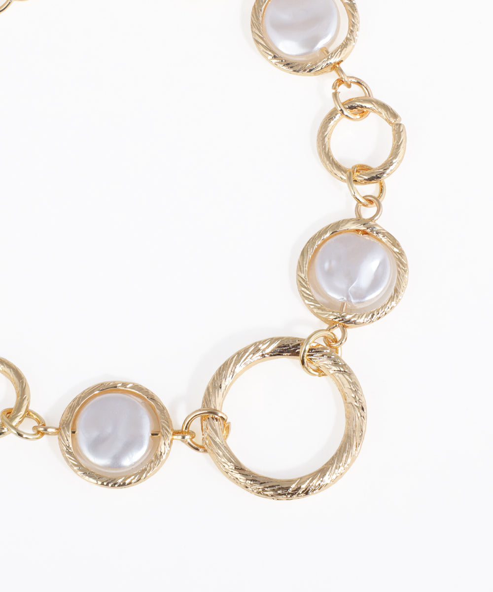 Gold necklace with circular links and white stones on a white background