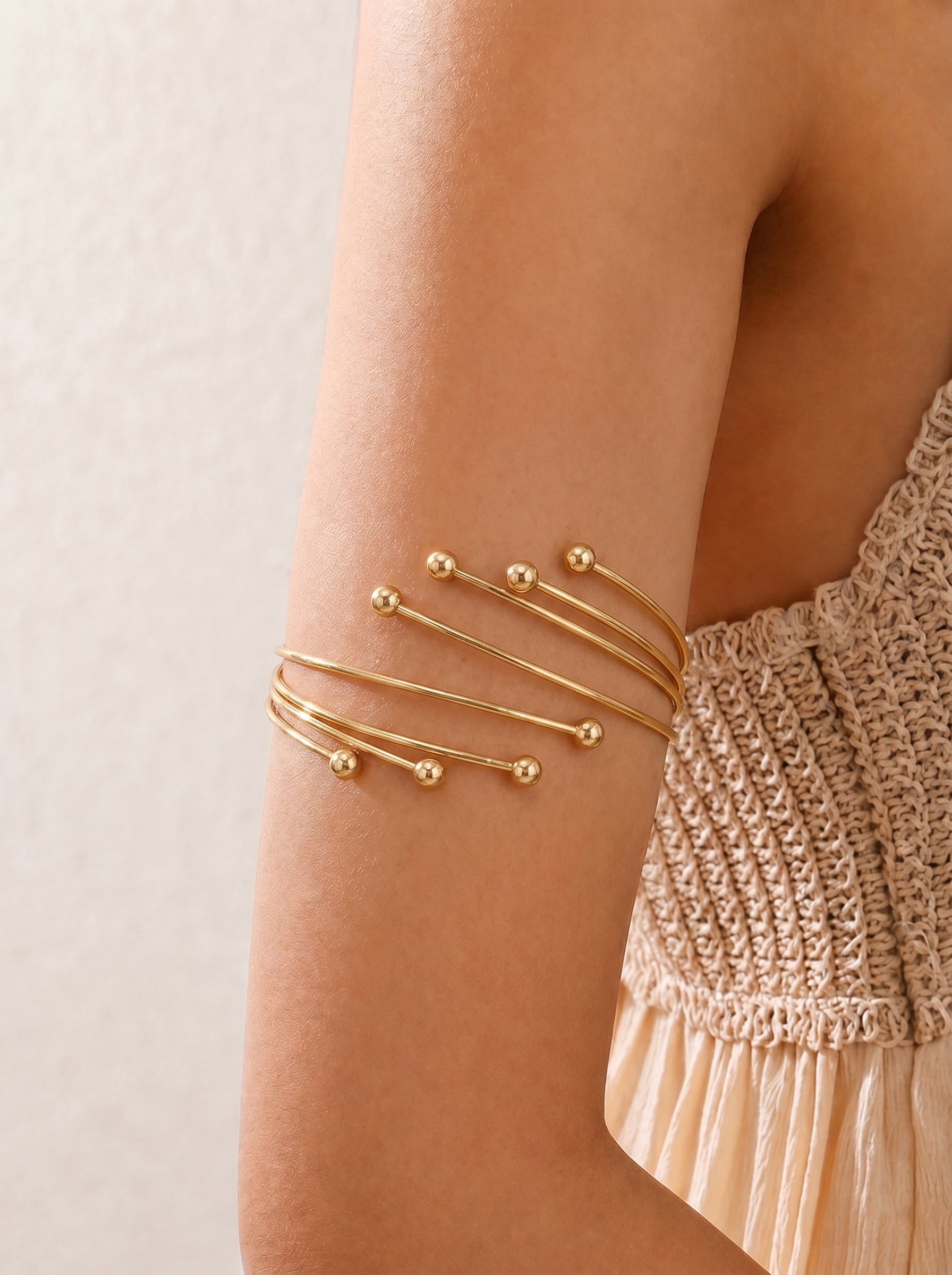 Gold bracelet on a wrist with a neutral background