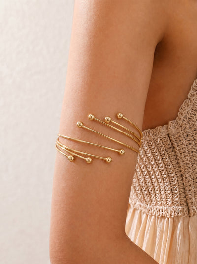 Gold bracelet on a wrist with a neutral background