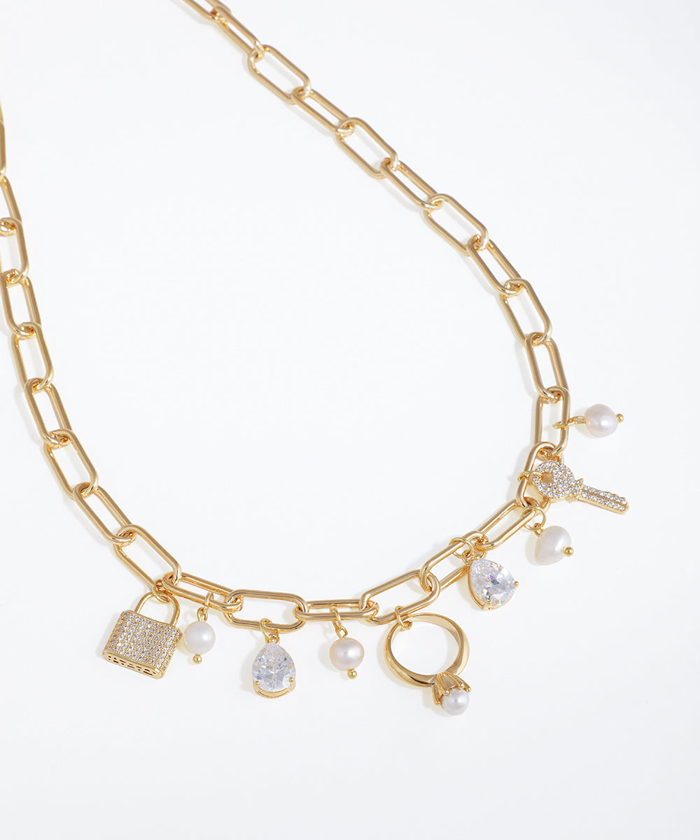 Gold chain necklace with various charms on a white background