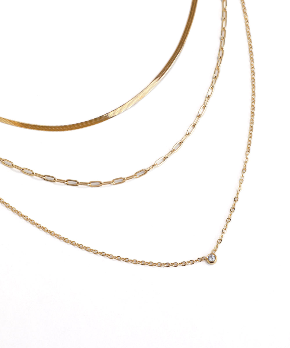 Three gold necklaces of different styles on a white background
