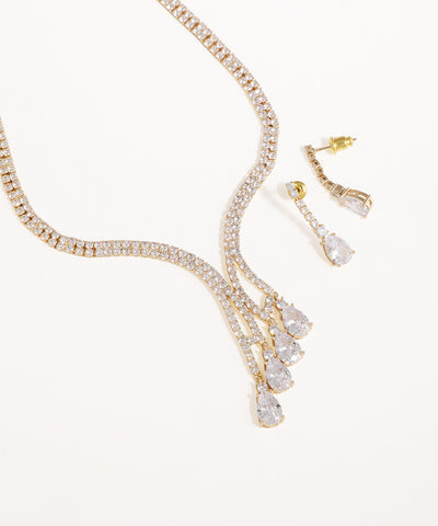 Gold necklace and earrings with clear stones on a white background