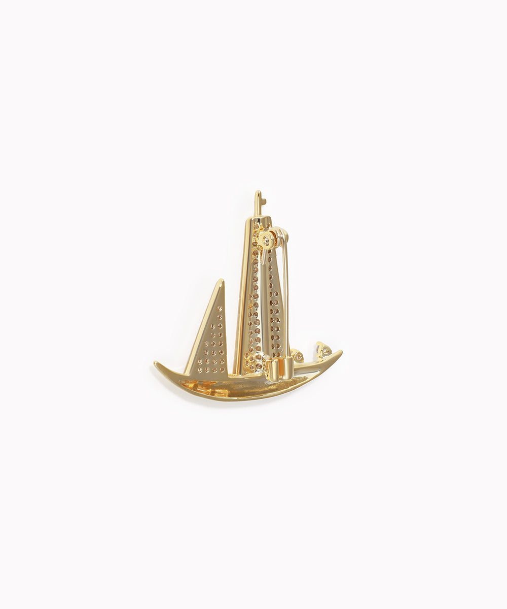 Gold sailboat charm on a white background