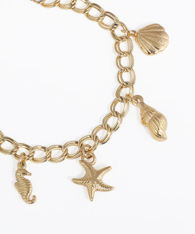 Gold charm bracelet with seashell, starfish, and seahorse charms on a white background