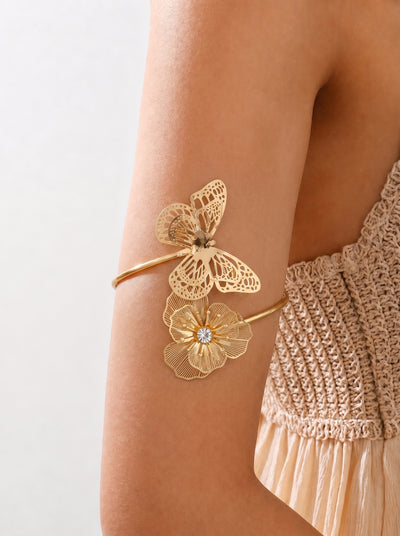 Gold floral bracelet on a person's wrist with a plain background