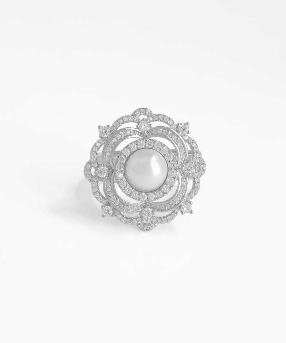 Silver brooch with a central pearl and diamond-like stones on a white background