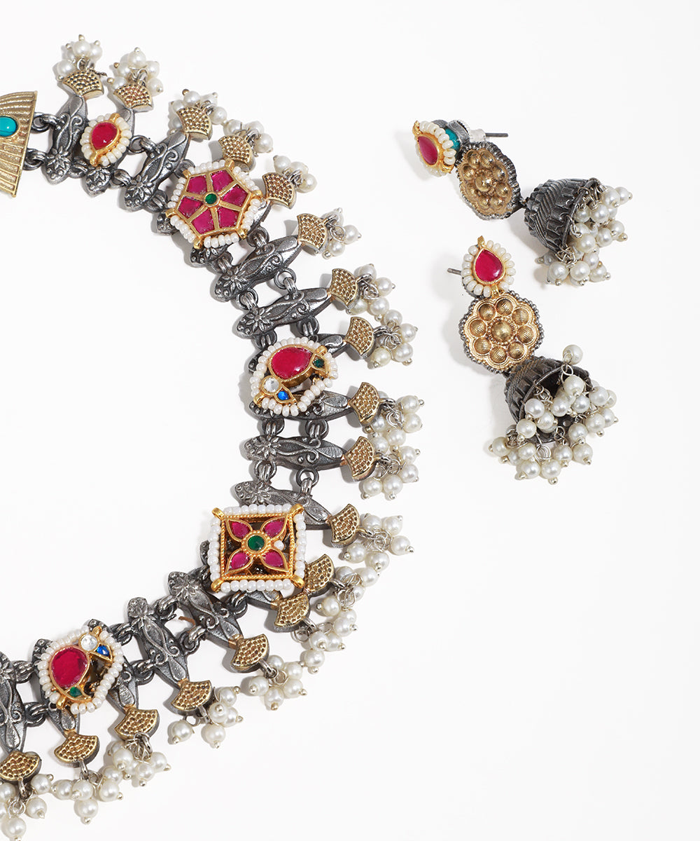 Ornate necklace and earrings with gemstones and pearls on a white background