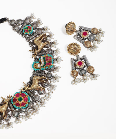 Ornate necklace and earrings with colorful gemstones on a white background