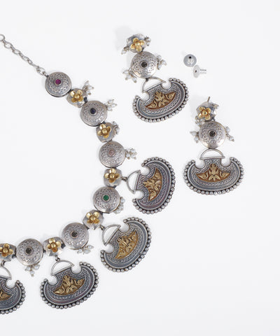 Ornate silver and gold necklace with intricate designs on a white background
