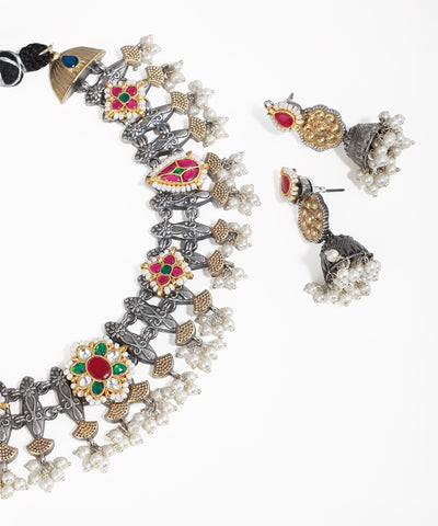 Ornate necklace and earrings with gemstones on a white background