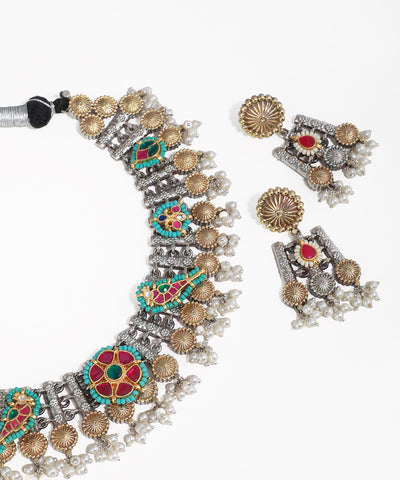 Ornate necklace and earrings with colorful gemstones on a white background