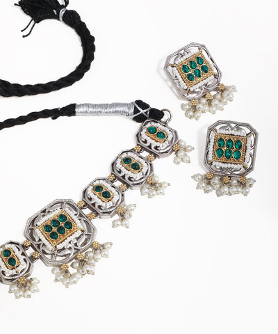 Jewelry set with necklace and earrings featuring green gemstones and pearl accents on a white background.