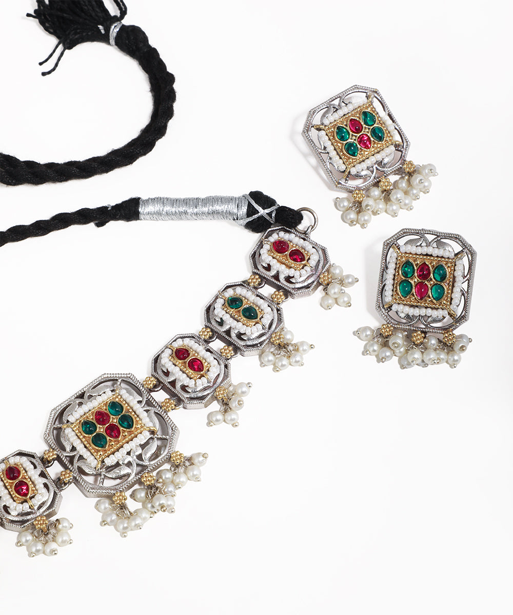 Ornate silver necklace with gemstones and pearls on a white background