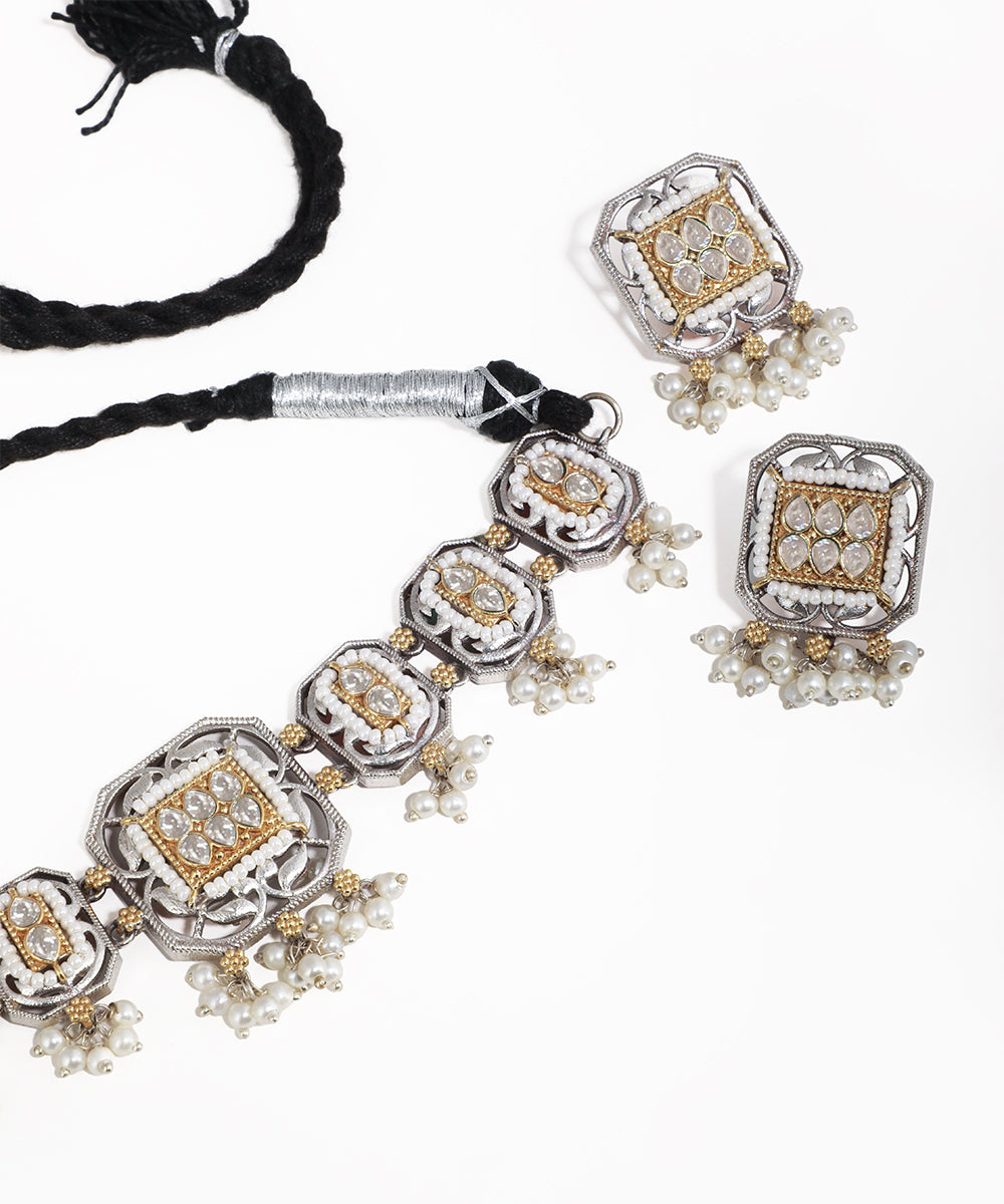 Ornate silver and gold necklace with matching earrings on a white background