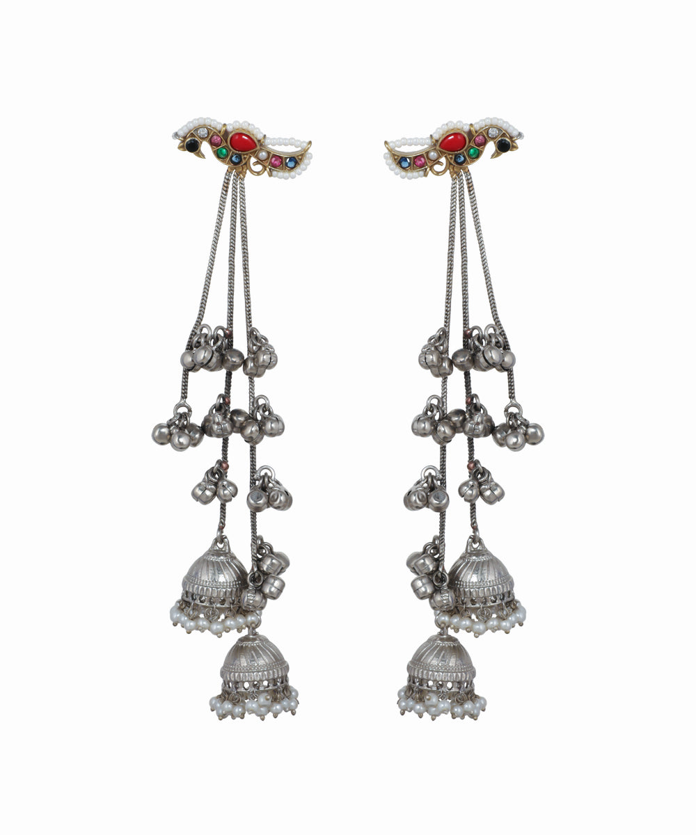 Pair of silver earrings with hanging bells and gemstone accents on a white background