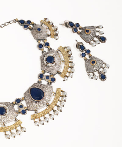 Ornate necklace and earrings with blue stones and gold accents on a white background