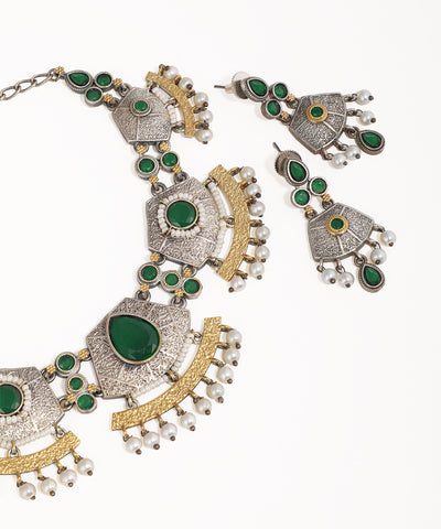 Ornate necklace and earrings with green gemstones and gold accents on a white background