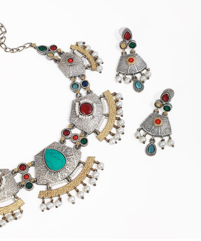 Ornate necklace and earrings with colorful gemstones on a white background
