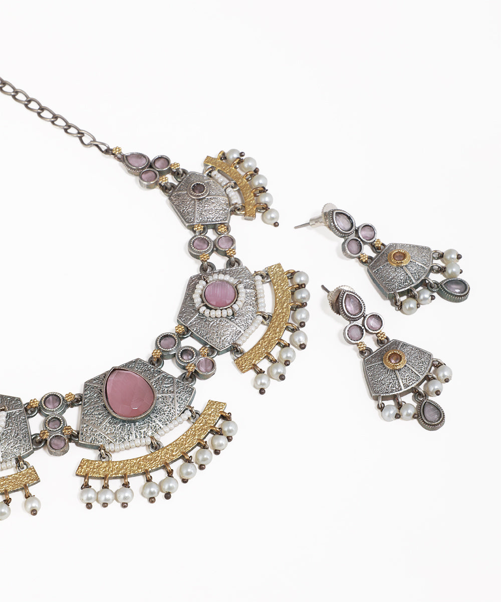 Ornate necklace and earrings set with pink stones on a white background