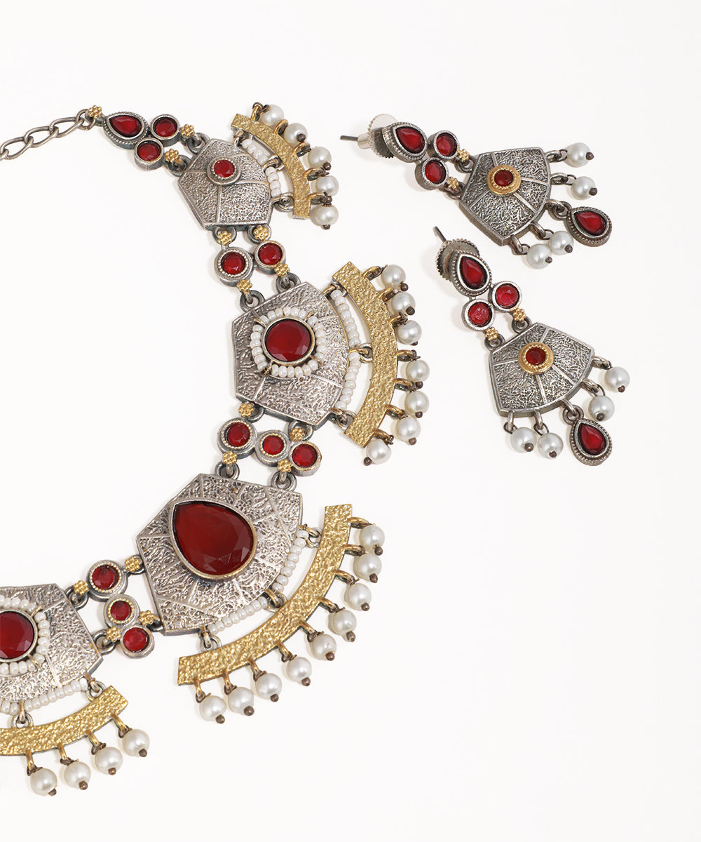 Ornate necklace and earrings set with red stones and gold accents on a white background