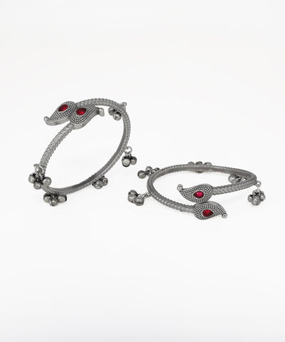 Pair of silver bangles with red stones on a white background