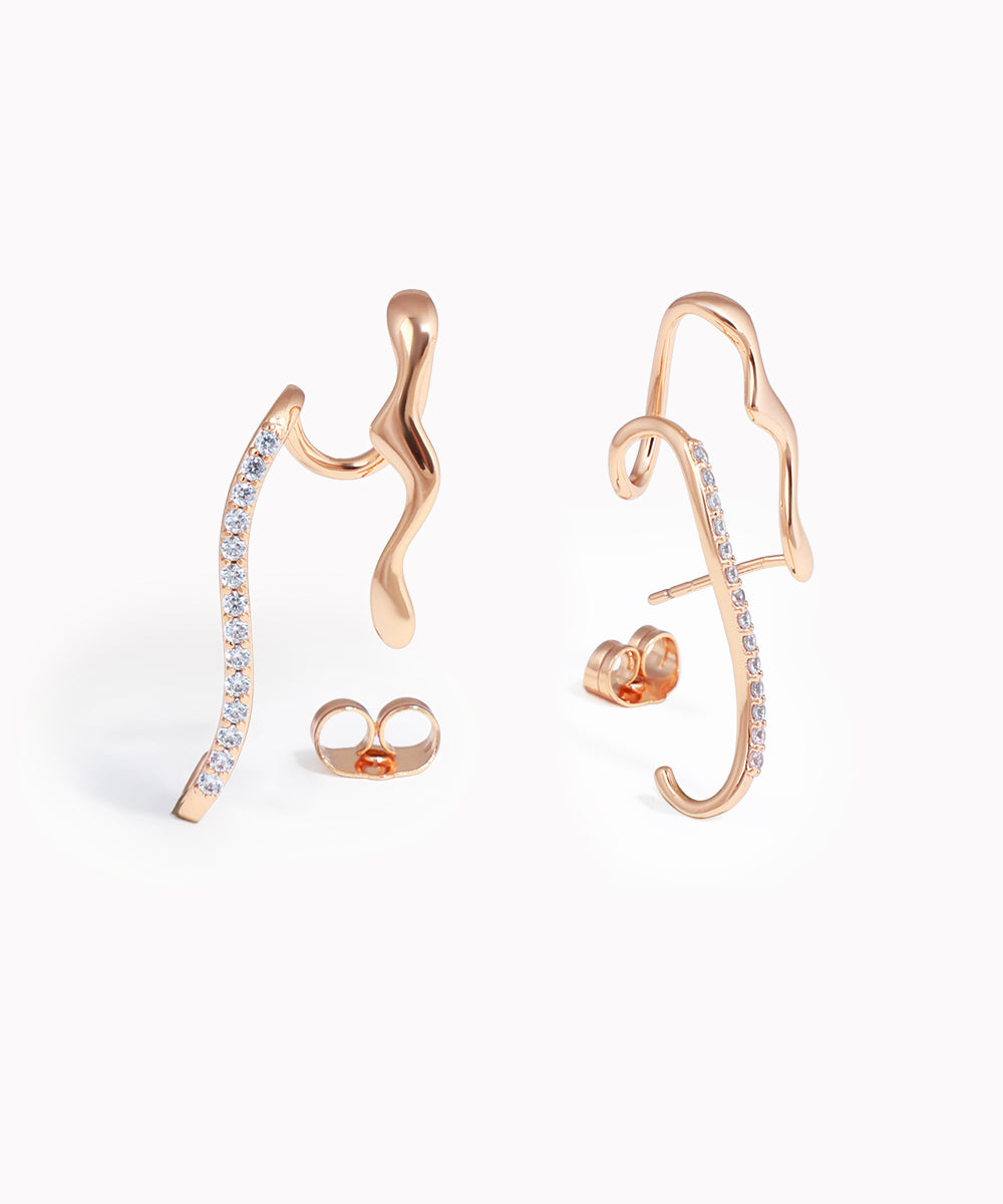 Rose gold ear cuff with embedded stones on a white background
