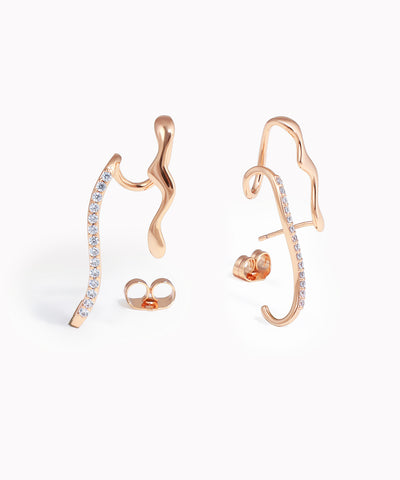 Rose gold ear cuff with embedded stones on a white background