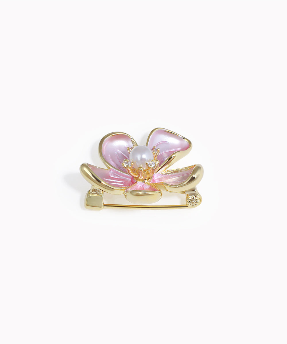 Pink butterfly-shaped brooch with gold accents on a white background