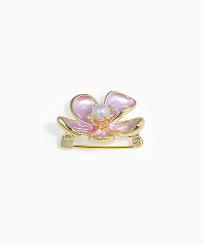 Pink butterfly-shaped brooch with gold accents on a white background