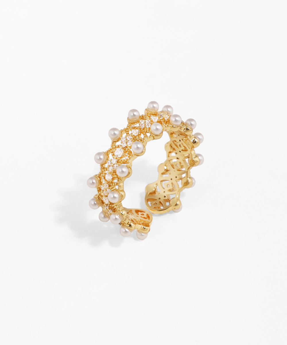 Gold-tone open ring with white faux pearls and clear CZ stones on an intricate band design.