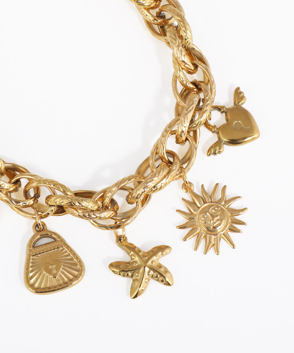 Gold chain bracelet with various charms on a white background