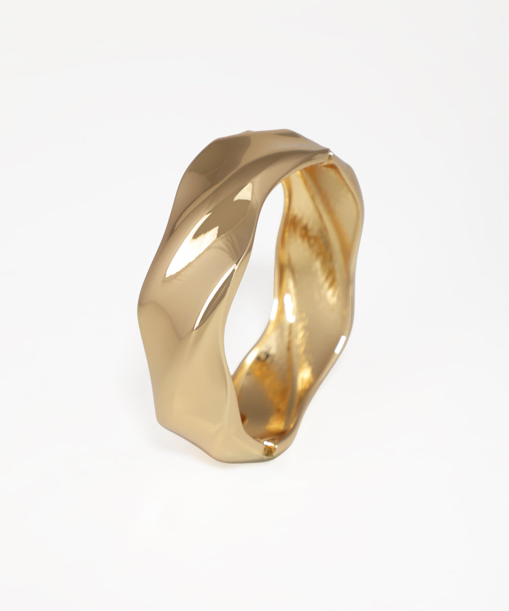 Gold ring with a twisted design on a white background
