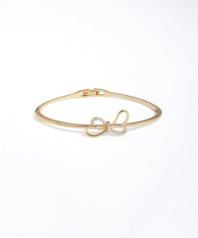 Gold bracelet with a bow charm on a white background