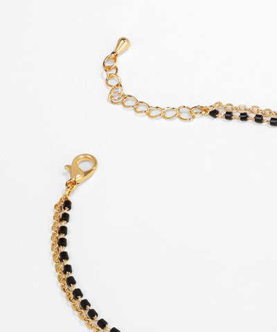 Gold bracelet with black beads on a white background