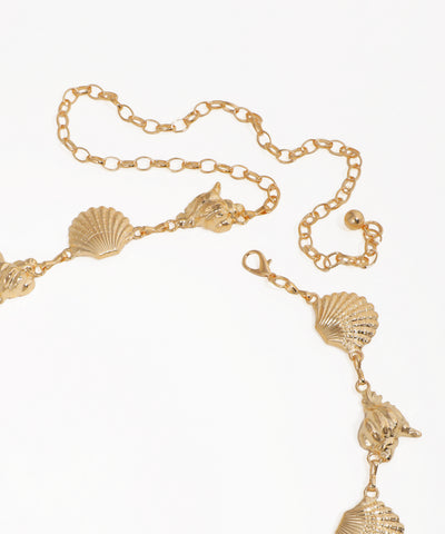 Gold necklace with shell and dolphin pendants on a white background