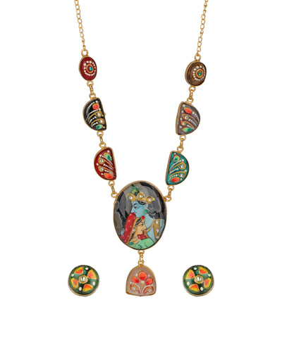 A gold-tone necklace with a central oval pendant depicting a blue-skinned figure, flanked by colorful enamel drop charms and matching oval stud earrings on a plain white background.
